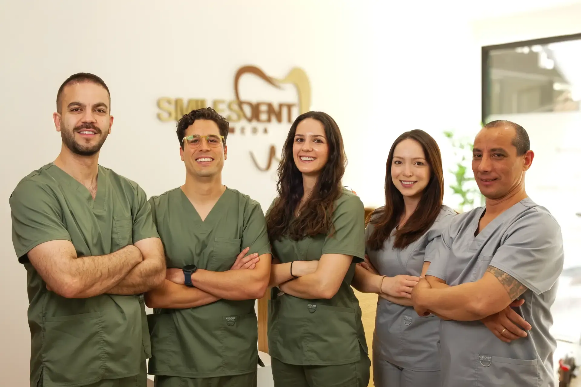 Equipo de dentistas de SmilesDent Alameda con uniforme verde oliva en la recepción de la clínica